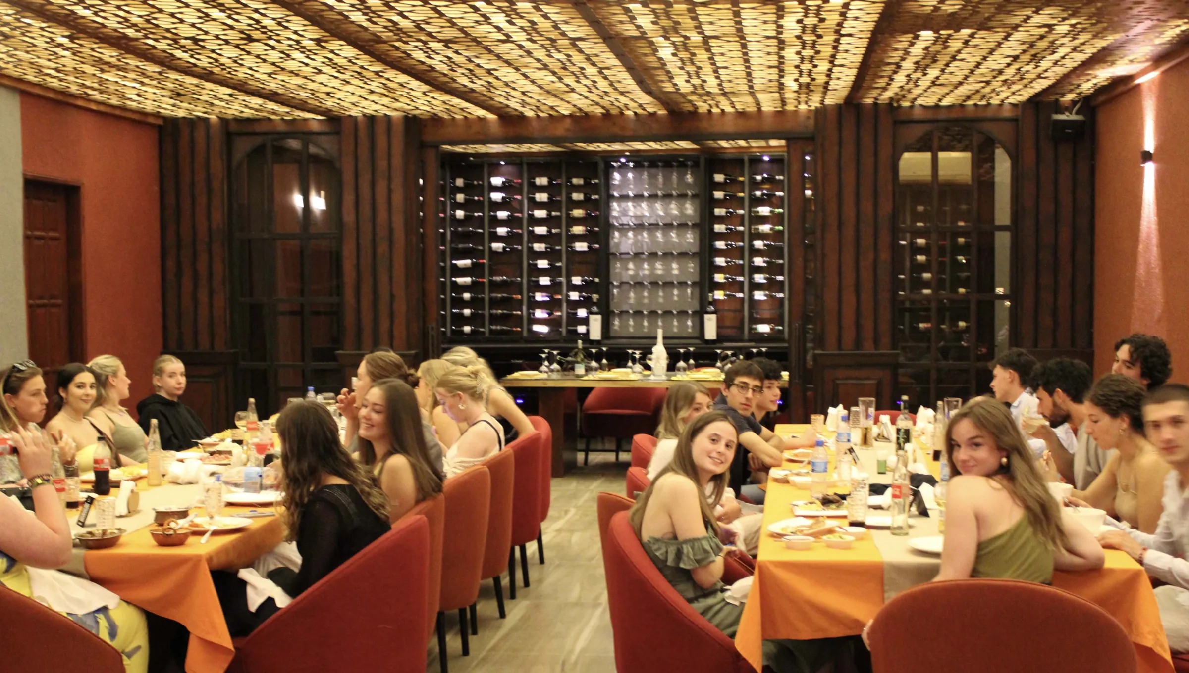 A long table of guests celebrating in Amber's dining room beneath the wine wall